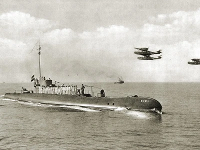 Hr.Ms.&nbsp;K 18&nbsp;bij binnenkomst in Soerabaja, 1935. In de lucht vliegen drie Dornier Do J-Wal vliegboten (foto: collectie NIMH)